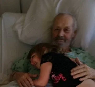 Ronald hugging grandson on hospital bed